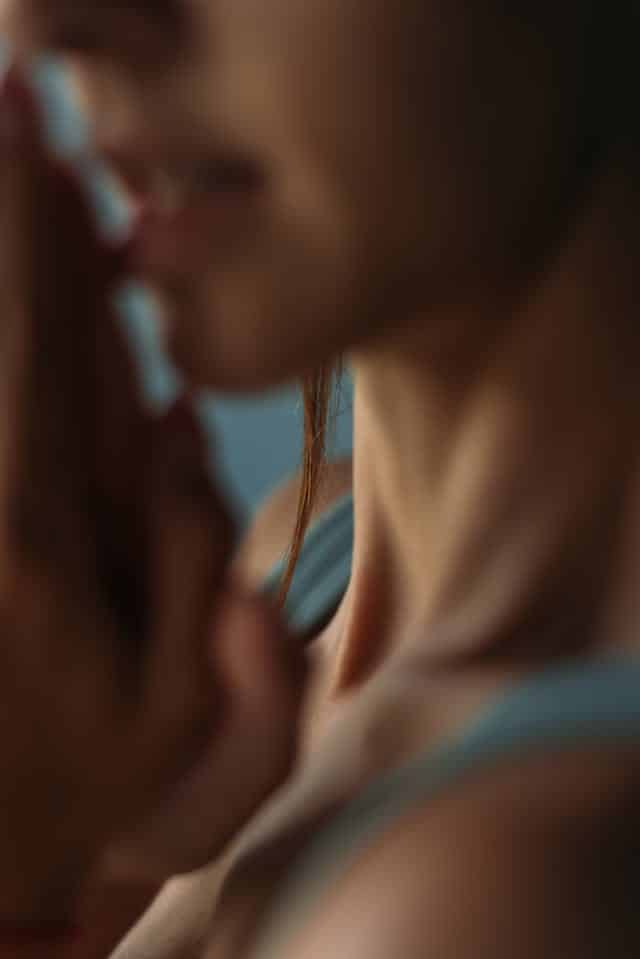 Mani giunte e volto di donna sfocati, atmosfera intima e raccolta.