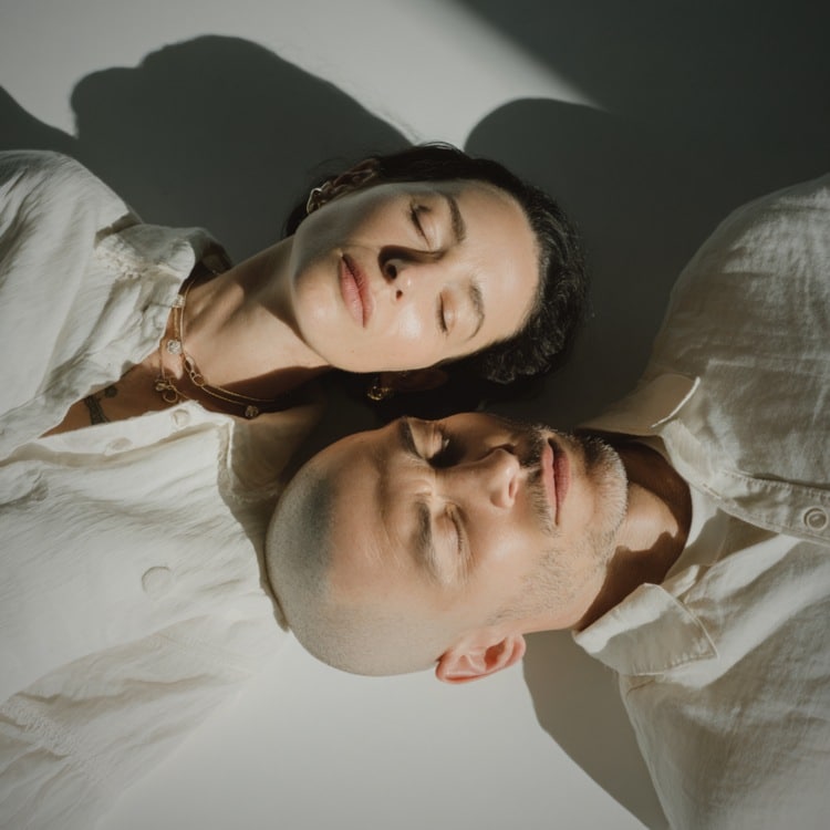 Coppia in aspetto meditativo sdraiata sul pavimento